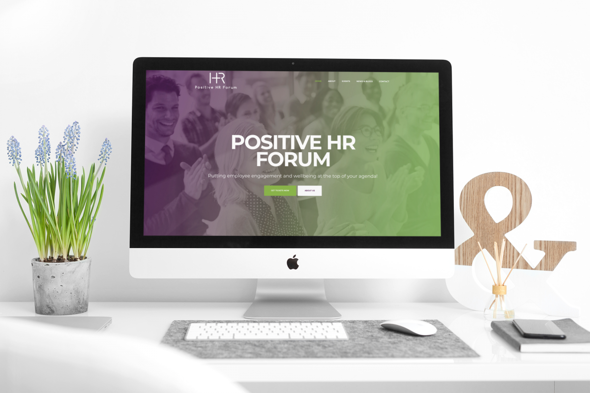 Positive HR’s Homepage design A mac computer on a desk showing The Positive HR Forum website homepage design